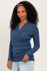 woman wearing a blue long sleeve wrap top with ruching details and a deep v-neckline