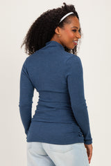woman wearing a dark blue long sleeve fitted top with a mock neck and gathered sides