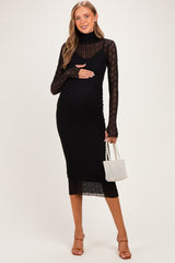 woman wearing a black maternity dress with a turtleneck and long sheer sleeves, holding her baby bump and a small purse