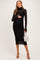 woman wearing a black maternity dress with a turtleneck and long sheer sleeves, holding her baby bump and a small purse