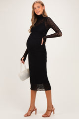 woman wearing a black ribbed maternity midi dress with long sleeves and a visible baby bump, holding a small white handbag