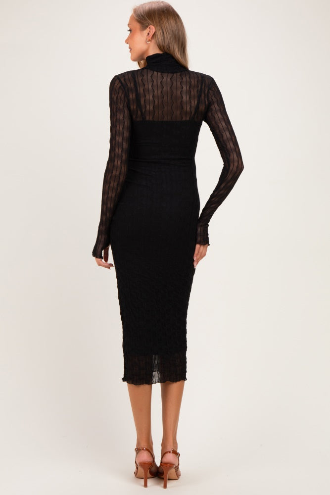woman wearing a black fitted maternity dress with long sleeves and a sheer back design
