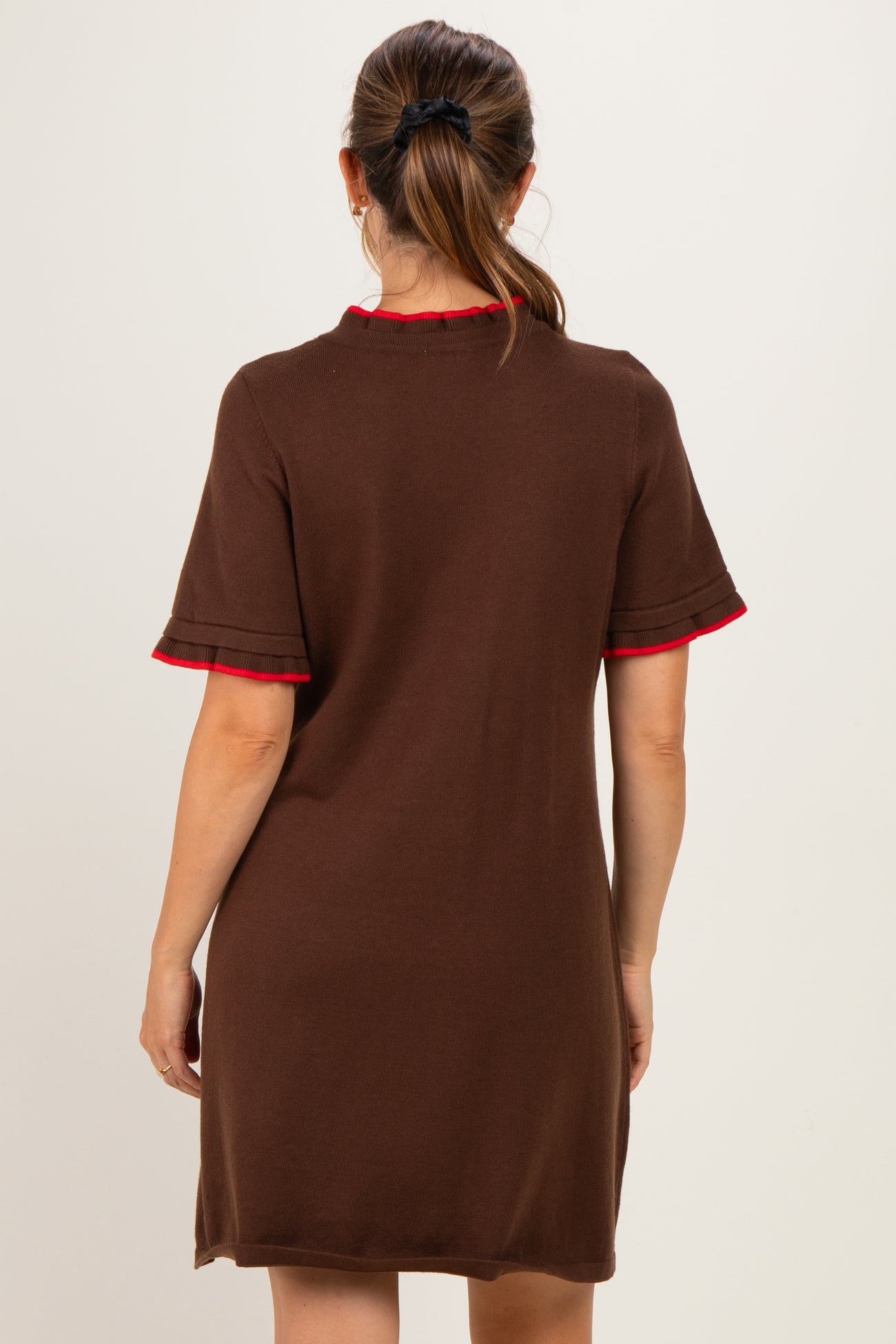 woman wearing a brown short sleeve maternity dress with red trim on the collar and sleeves, showing the back view