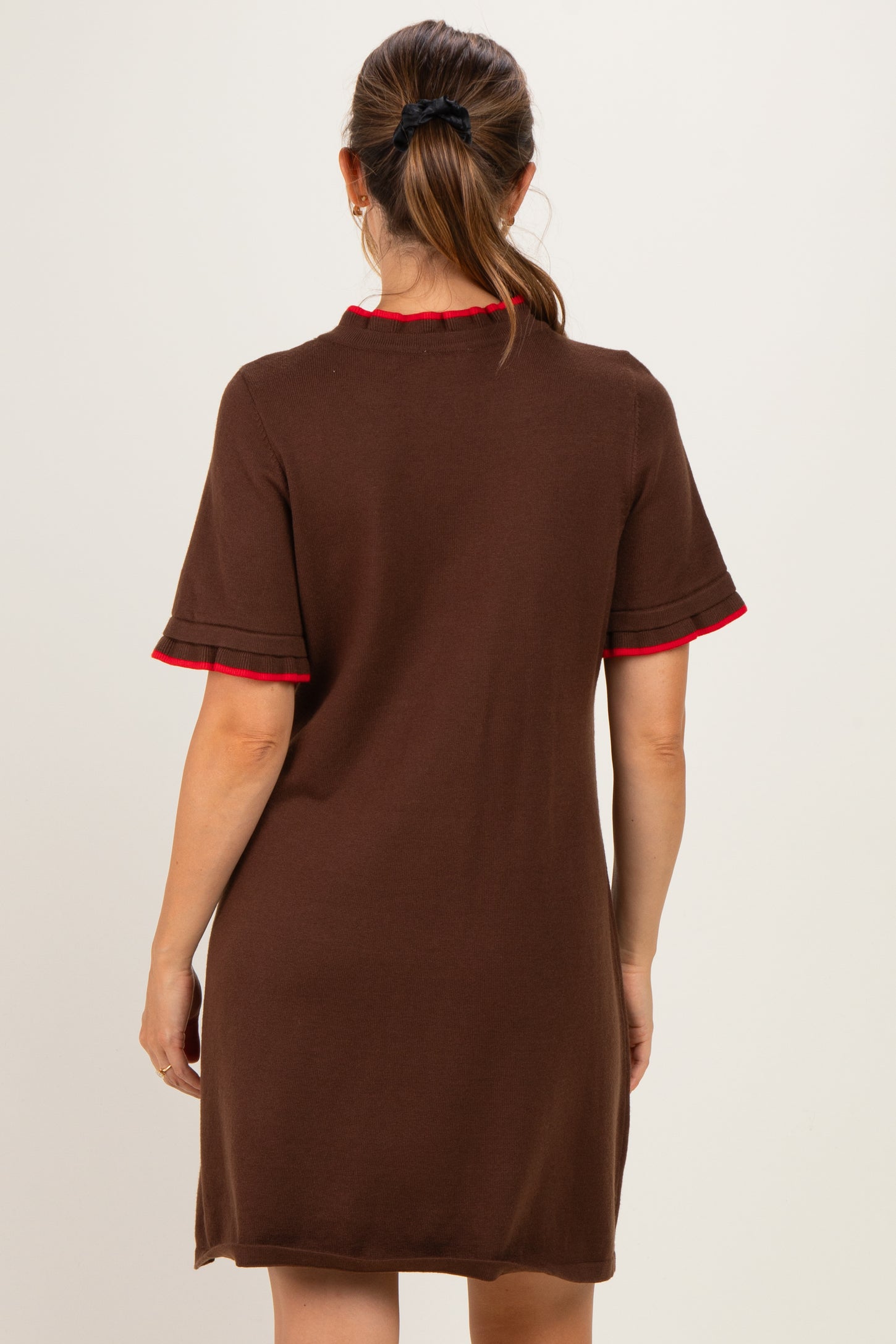 woman wearing a brown short sleeve maternity dress with red trim on the collar and sleeves, showing the back view