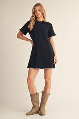 woman wearing a black short sleeve dress with ruffled sleeves and cowboy boots