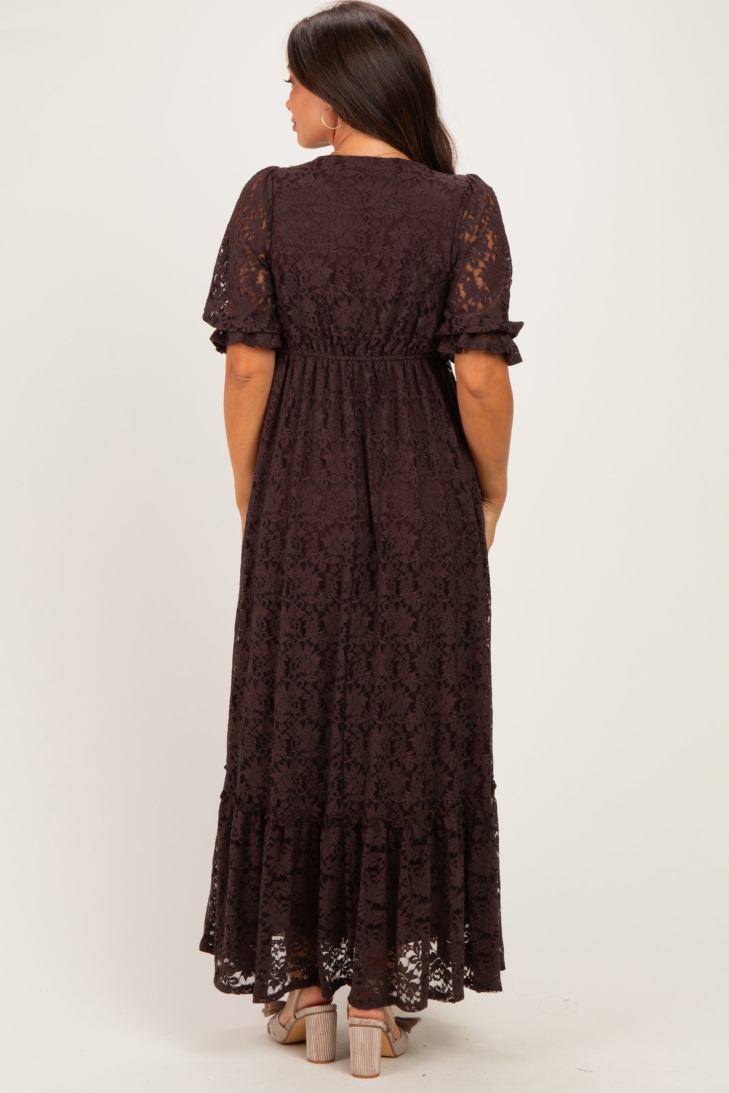 woman wearing a dark brown lace maternity maxi dress with short sleeves and a fitted waist, showing her baby bump from behind