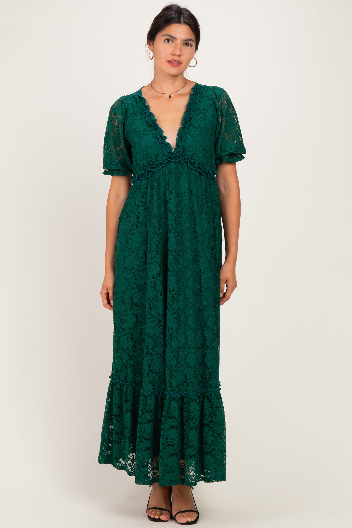 woman wearing a green lace maxi dress with short sleeves and ruffled details.