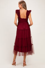 woman wearing a burgundy maternity dress with ruffled straps and tiered tulle details, showing the back view