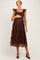 woman wearing a brown ruffled maternity dress with tiered design and holding her baby bump