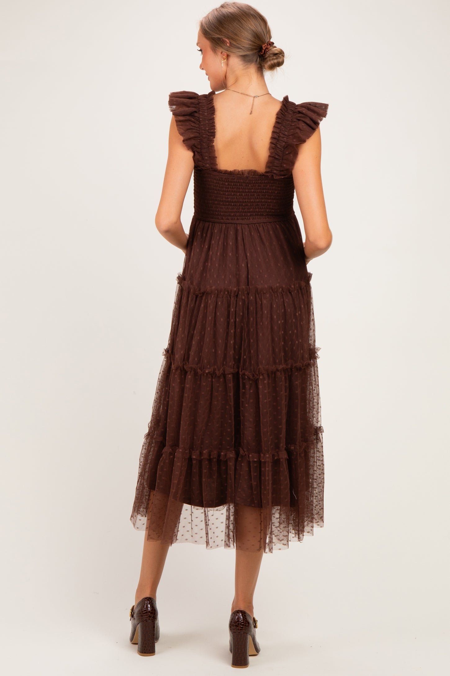 woman wearing a brown tiered maternity dress with ruffle straps and a smocked back, showcasing a flowing design