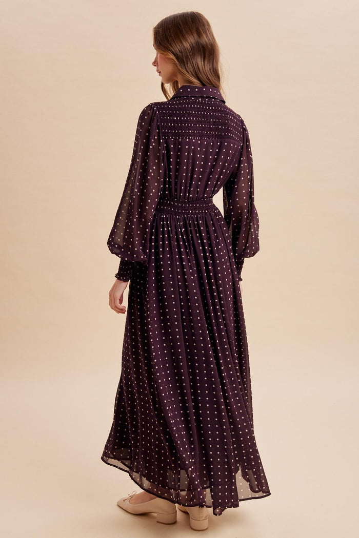 woman wearing a long purple polka dot dress with bell sleeves and a cinched waist, viewed from the back