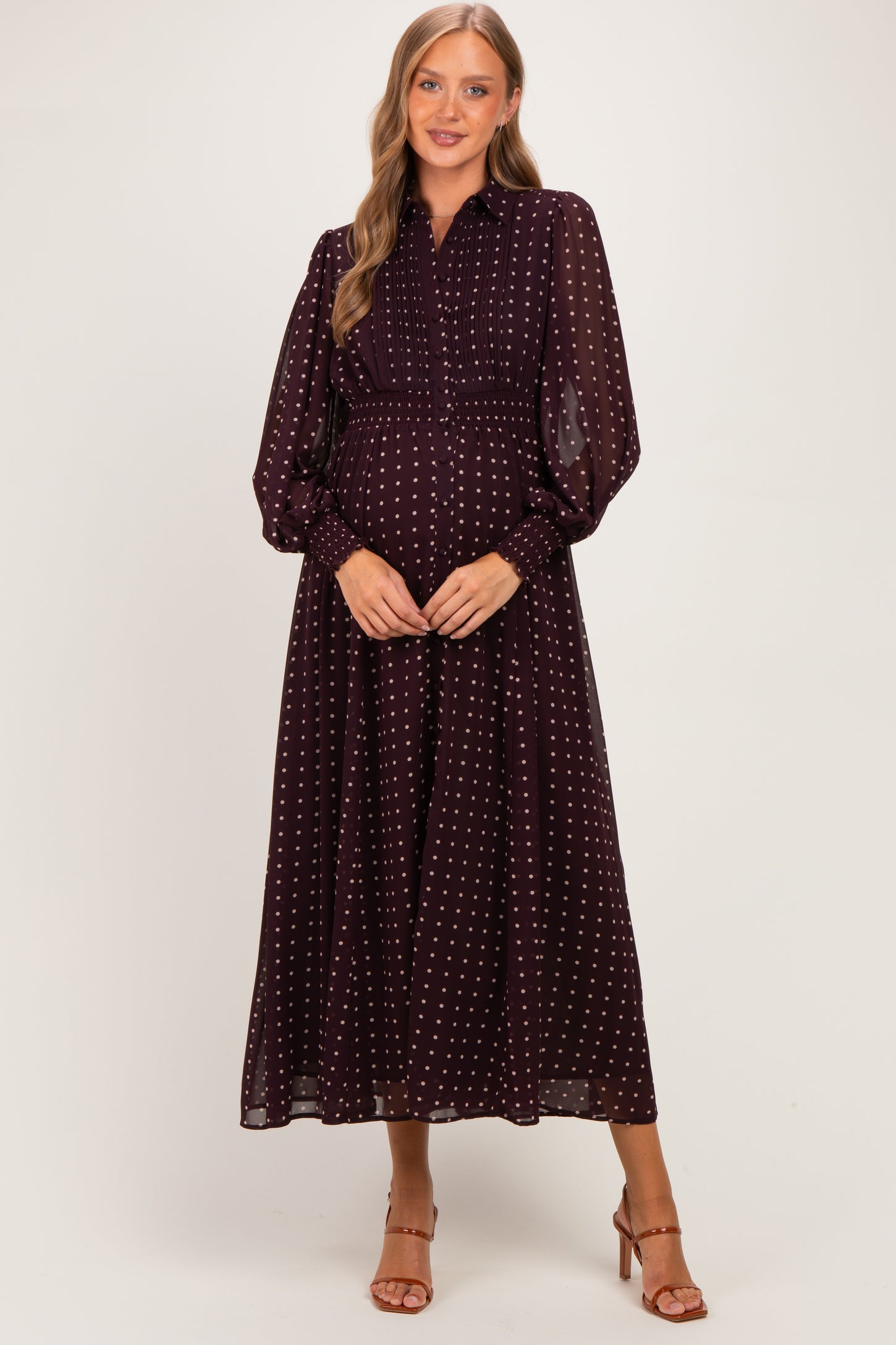 woman wearing a burgundy maternity maxi dress with white polka dots and long sleeves, showing her baby bump