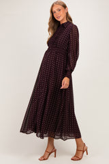 woman wearing a burgundy maternity dress with white polka dots and long sleeves, showcasing her baby bump