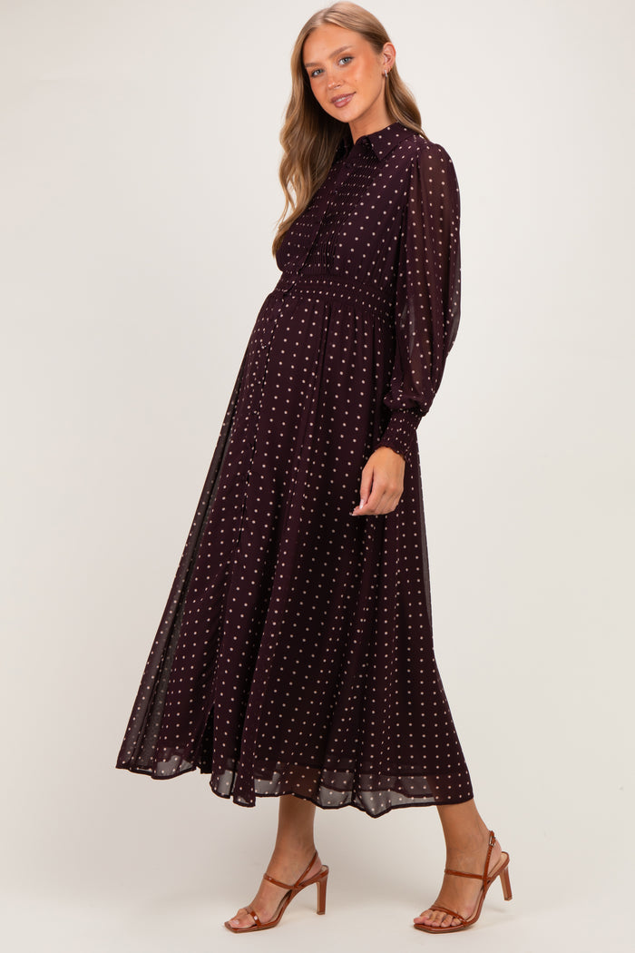 woman wearing a burgundy maternity dress with white polka dots and long sleeves, showcasing her baby bump