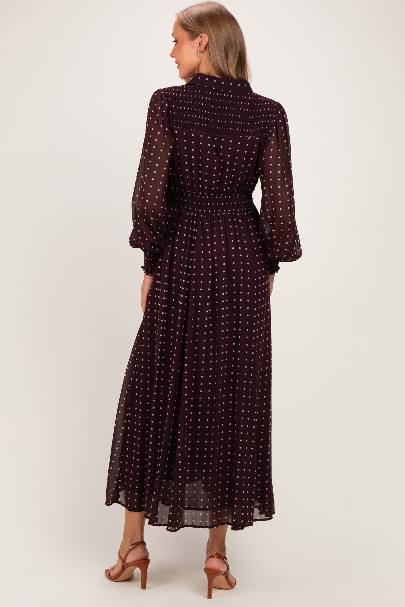 woman wearing a burgundy polka dot maternity dress with long sleeves and a cinched waist, seen from the back
