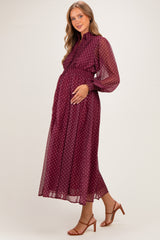 woman wearing a burgundy maternity maxi dress with polka dots and long sleeves, holding her baby bump