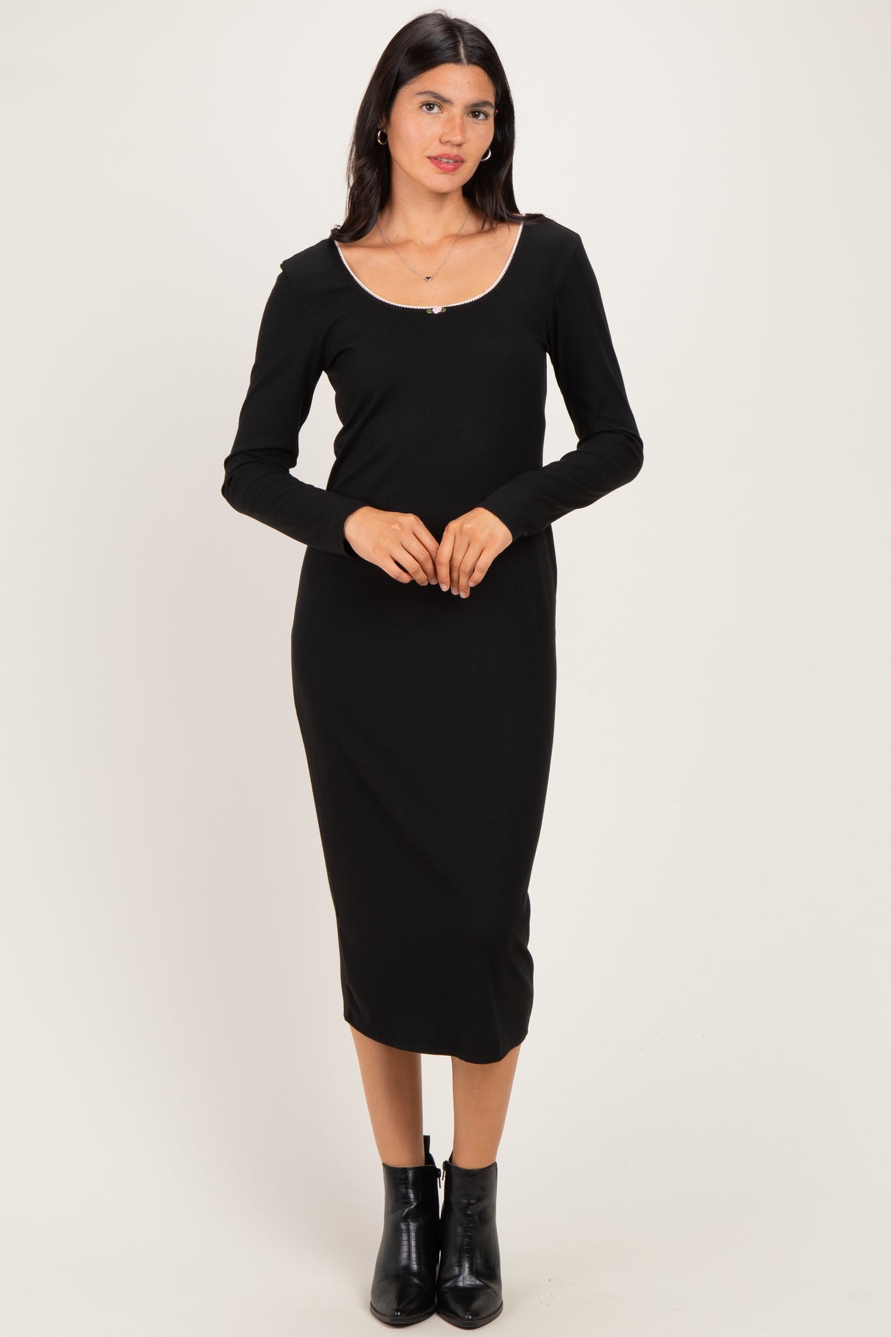 woman wearing a black long sleeve midi dress with a scoop neckline and a fitted silhouette