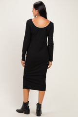woman wearing a black long sleeve fitted midi dress with a low back and side slit, paired with black ankle boots