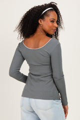 woman wearing a gray ribbed long sleeve top with a scoop back and styled hair with a headband
