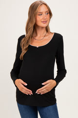 woman wearing a black long sleeve maternity top with a scoop neckline and holding her baby bump