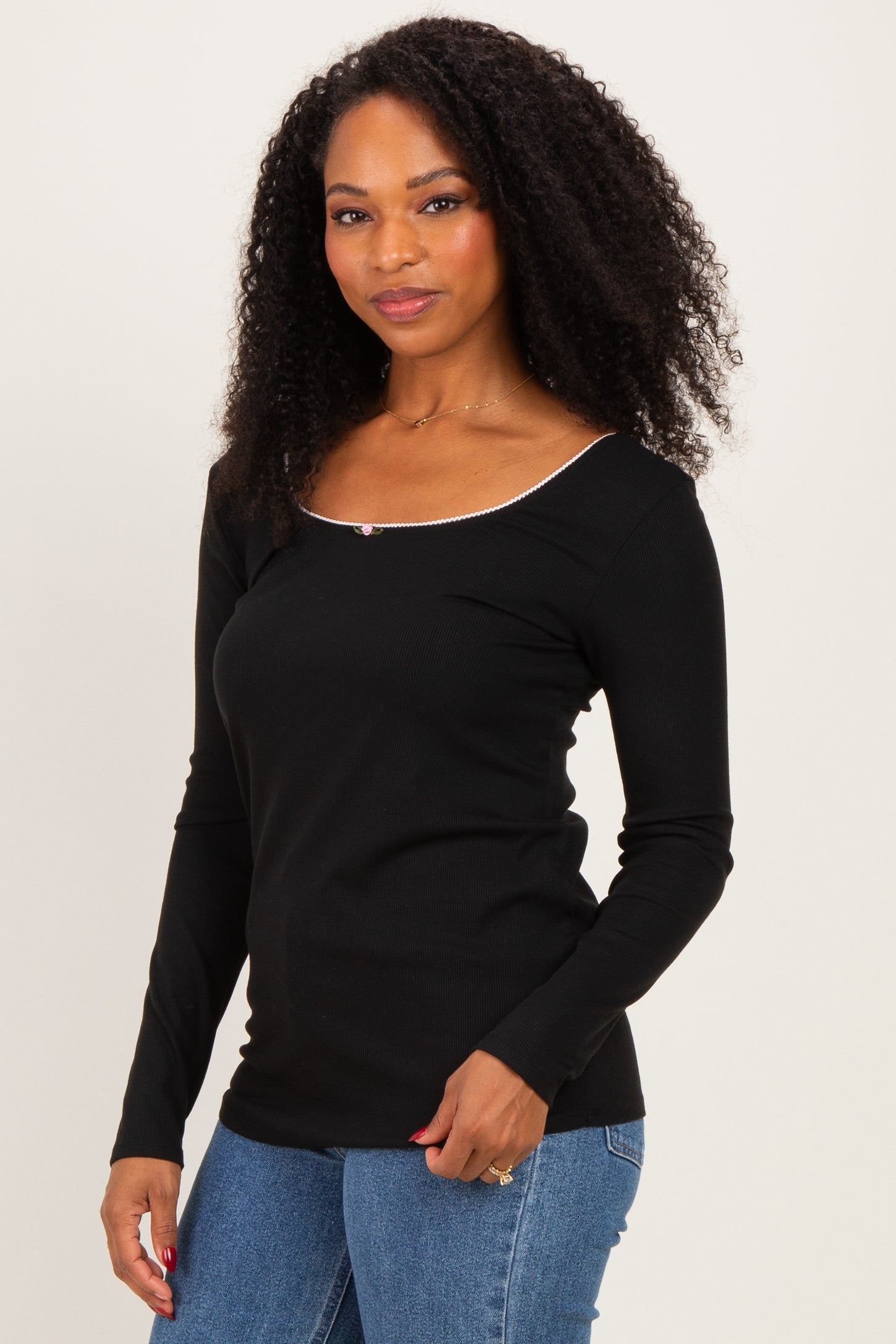 woman wearing a black long sleeve top with a scoop neckline and decorative trim