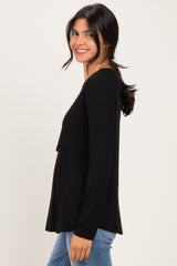woman wearing a black long sleeve top with a layered design and smiling