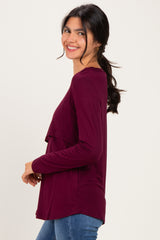 woman wearing a burgundy long sleeve top featuring a double layered design, smiling with hair in a ponytail