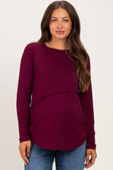 woman wearing a burgundy long sleeve maternity top with a layered design and a visible baby bump