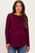 woman wearing a burgundy long sleeve maternity top with a layered design and a visible baby bump