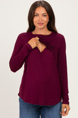 woman wearing a plum long sleeve maternity top with ruched detail for easy nursing access and a visible baby bump