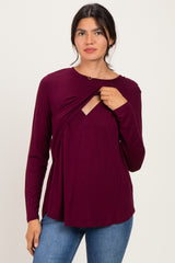 woman wearing a burgundy long sleeve top with a twist front detail and a v-neck opening