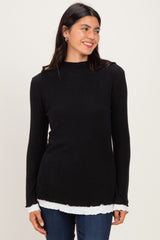 woman wearing a black ribbed long sleeve top with a white layered hem and smiling