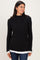 woman wearing a black ribbed long sleeve top with a white layered hem and smiling