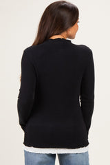 woman wearing a black ribbed maternity top with long sleeves and a scalloped neckline, view from the back