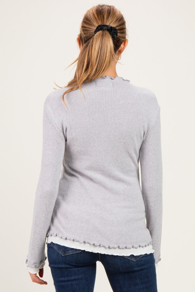 woman wearing a light gray maternity long sleeve top with a ruffled hem, viewed from the back