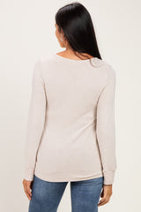 woman wearing a beige long sleeve sweater, shown from the back, paired with blue jeans