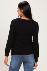 woman wearing a black long sleeve sweater with a fitted style and round neckline, seen from the back