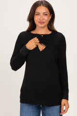 woman wearing a black maternity sweater with a scoop neckline and a layered design for easy nursing access
