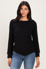 woman wearing a black long sleeve top with a layered design and relaxed fit, paired with blue jeans