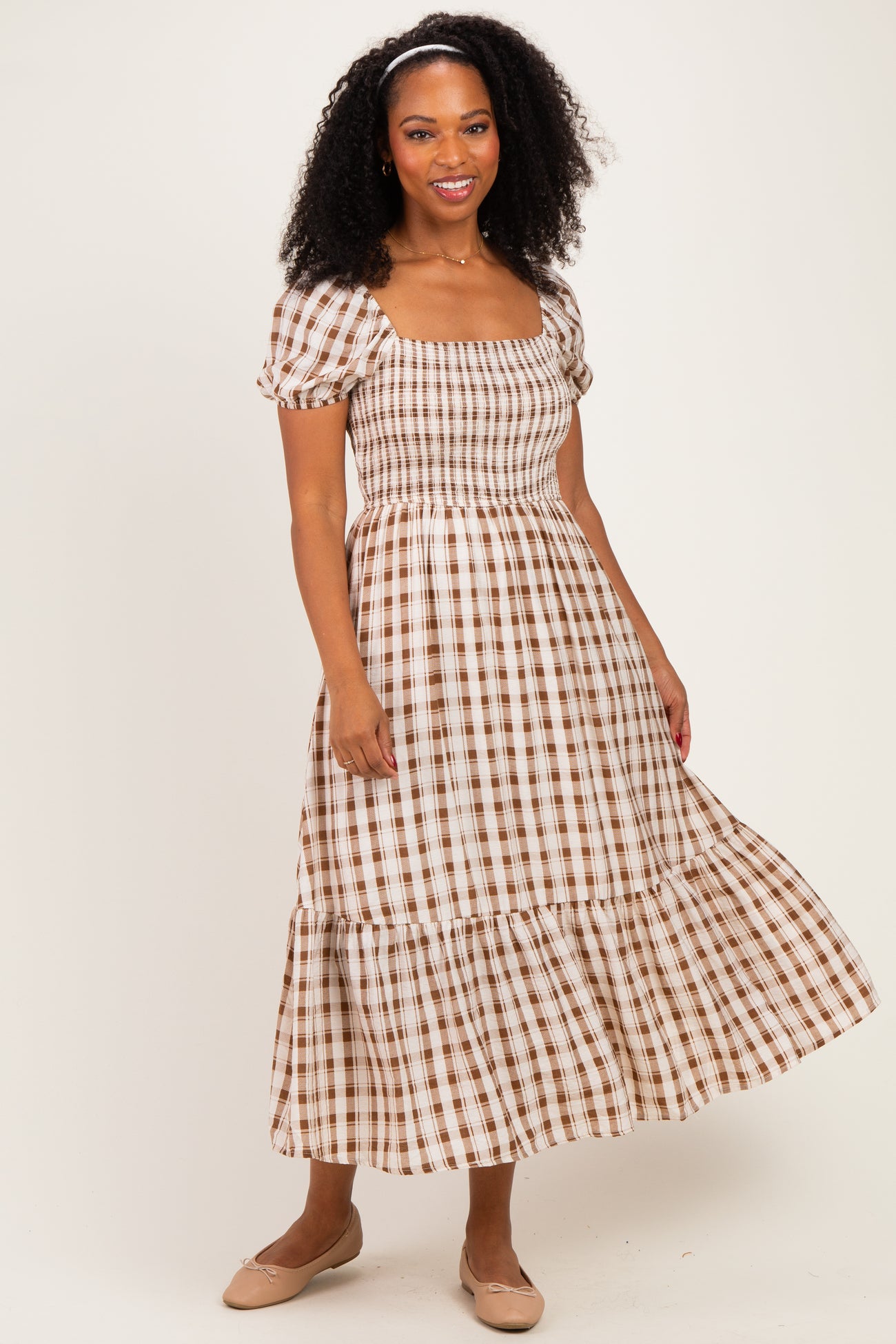 woman wearing a brown and white checkered midi dress with puff sleeves and a tiered skirt