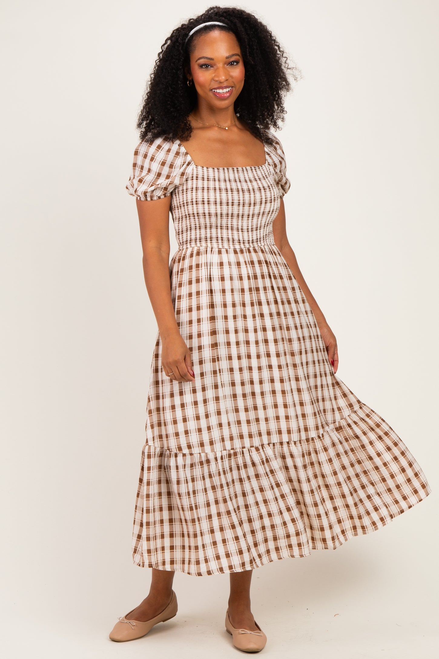 woman wearing a brown and white checkered midi dress with puff sleeves and a tiered skirt