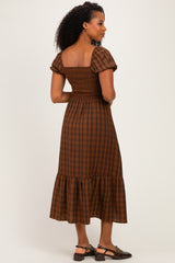 woman wearing a brown plaid puff sleeve midi dress with a smocked bodice and ruffled hem, viewed from the back