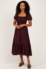 woman wearing a burgundy and black plaid maxi dress with puff sleeves and a smocked bodice