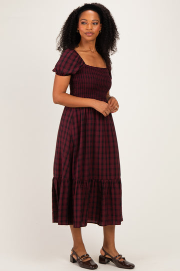 woman wearing a burgundy and black plaid midi dress with puff sleeves and a smocked bodice