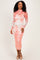 woman wearing a floral lace long sleeve bodycon dress in coral and white, standing and smiling