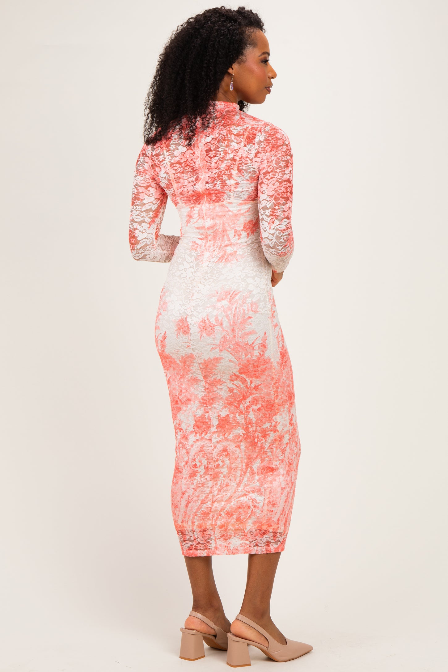woman wearing a floral lace midi dress in coral and white with long sleeves and a high neckline