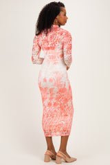 woman wearing a floral lace midi dress in coral and white with long sleeves and a high neckline