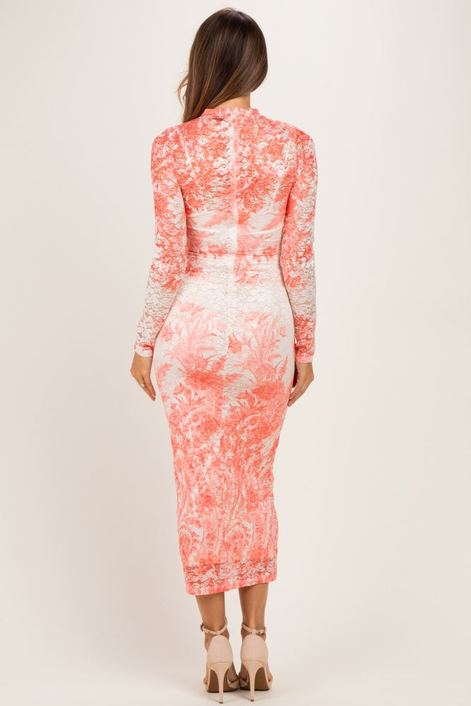 woman wearing a coral floral lace maternity dress with long sleeves, showing a fitted silhouette and knee-length hem