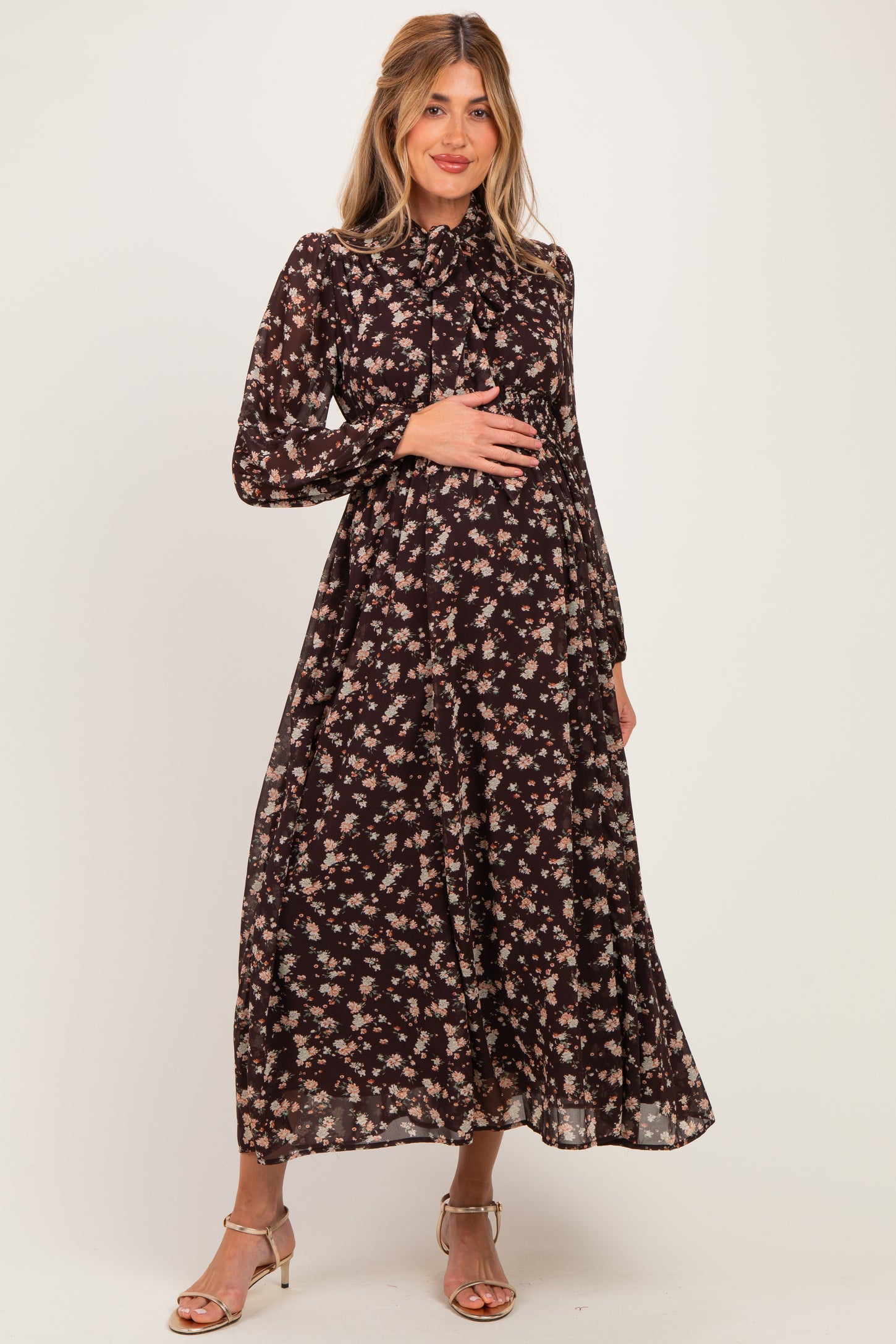 woman wearing a black floral maternity maxi dress and holding her baby bump