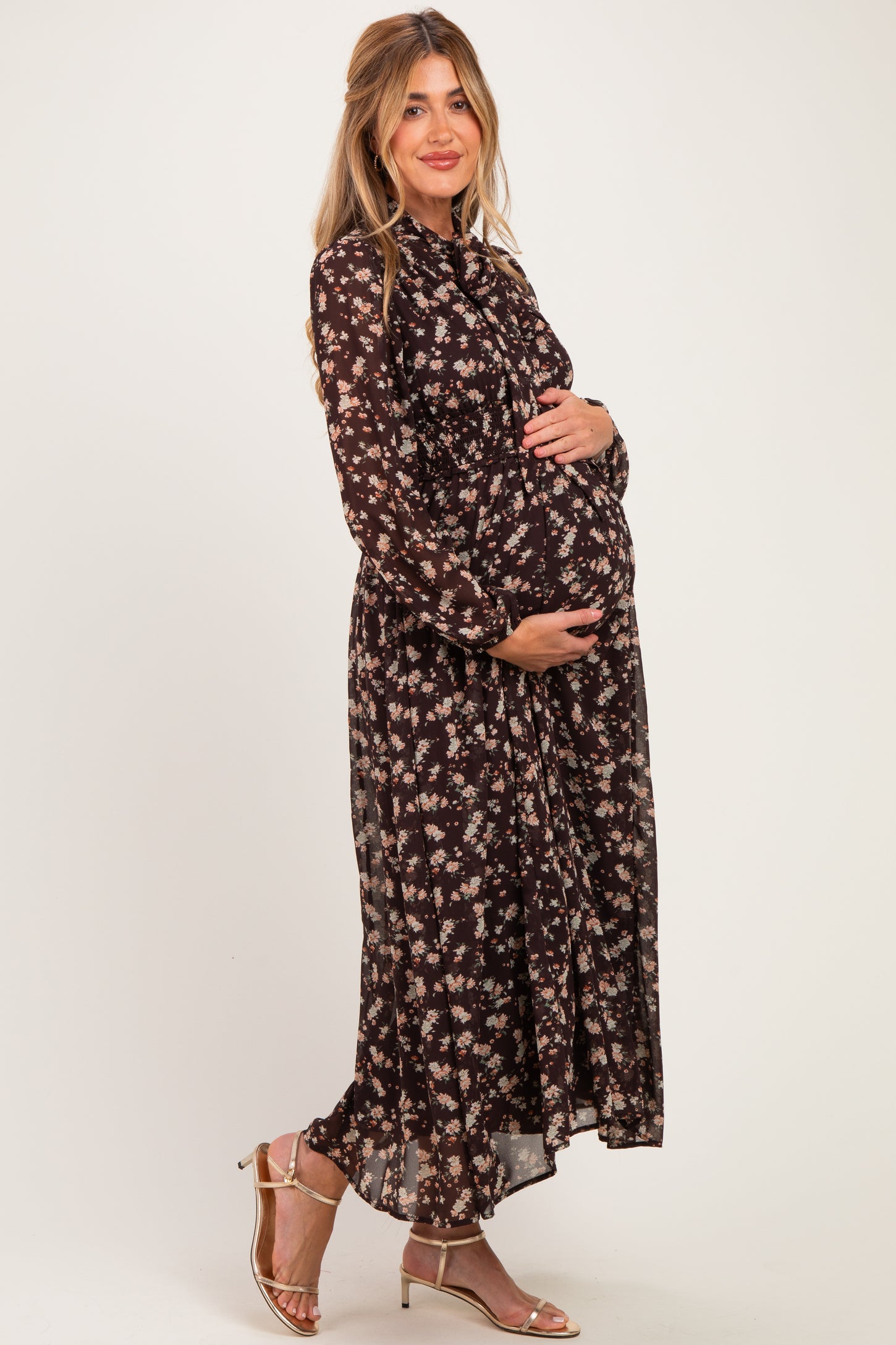 woman wearing a black floral maternity maxi dress and holding her baby bump